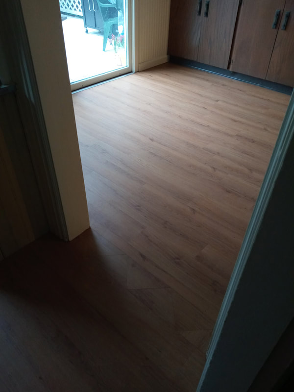 Natural wood flooring installation in empty room that leads to porch slider
